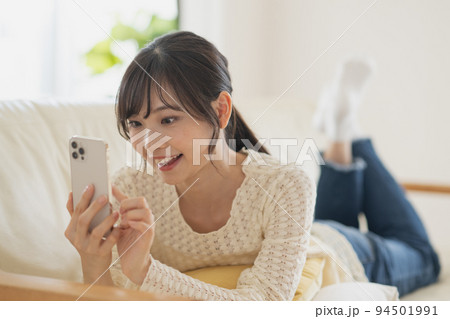 スマホ・スマートフォンを見る笑顔の女性 94501991