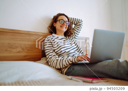 Young female freelancer works and makes notes while working at home in quarantine lockdown. Freelancer. Young female freelancer works and makes notes while working at home in quarantine lockdown. Freelancer. 94503209