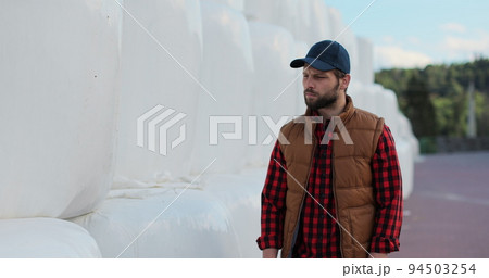 Close up of professional agronomist walking hay stack on season countryside. Agribusiness owner check bales pile at autumn farmland. Modern organic agribusiness. Close up of professional agronomist walking hay stack on season countryside. Agribusiness owner check bales pile at autumn farmland. Modern organic agribusiness. 94503254