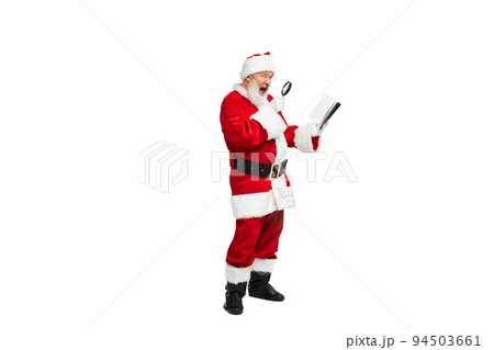 Portrait of senior man in image of Santa Claus looking on notes in magnifying glass isolated over white background 94503661