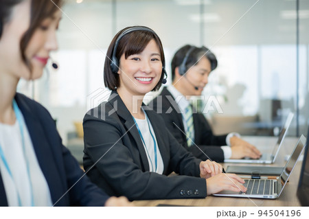 コールセンターで働く笑顔の若い女性 コールセンターで働く笑顔の若い女性 94504196