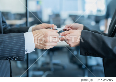 名刺交換をするミドル男性と若い女性 顔無し 名刺交換をするミドル男性と若い女性 顔無し 94504205