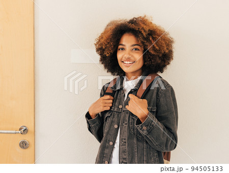 Portrait of a young woman with backpack at wall in high school	 94505133