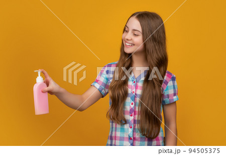 smiling kid with liquid soap bottle on yellow background 94505375