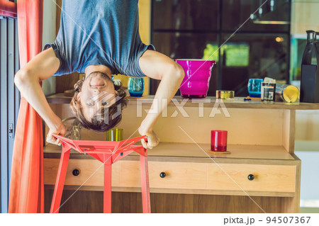 A man stands on his hands upside down in the kitchen 94507367