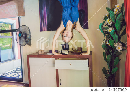 A woman is standing on his hands upside down in the living room 94507369