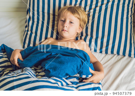 The cute boy woke up in his bed. Children sleep concept The cute boy woke up in his bed. Children sleep concept 94507379