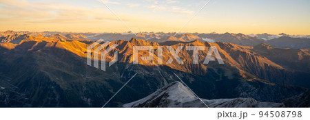 Alpine mountain peaks illuminated by rising sun Alpine mountain peaks illuminated by rising sun 94508798