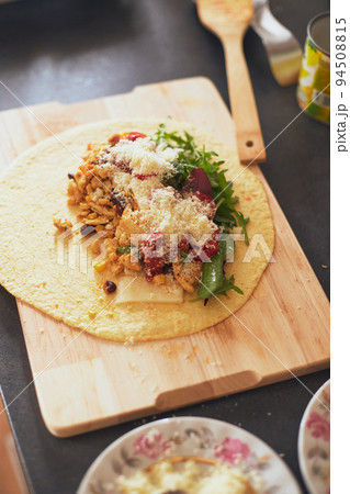 Cooking burrito, Mexican food at home. Grilled wheat tortilla stuffed with cheese, chicken, beans, corn, lettuce, tomato and sauce 94508815