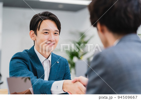 笑顔で握手を交わすビジネスマン 94509667