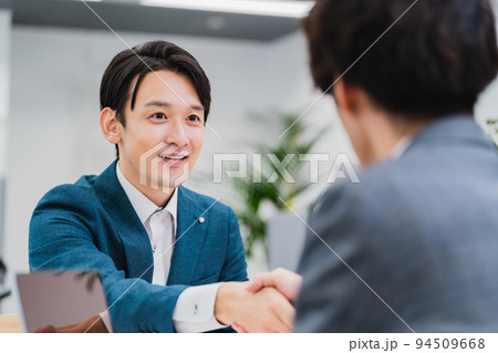 笑顔で握手を交わすビジネスマン 94509668