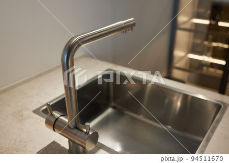 Black kitchen sink and Tap water in the kitchen. The interior of the kitchen room of the apartment. Built-In Appliances. Kitchen Appliance. Domestic Appliances. 94511670