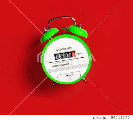 Green Electric meter with alarm clock on a red background Green Electric meter with alarm clock on a red background 94512179