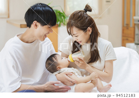 赤ちゃんにミルクをあげる夫婦 94512183
