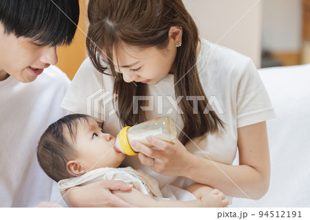 赤ちゃんにミルクをあげる夫婦 94512191