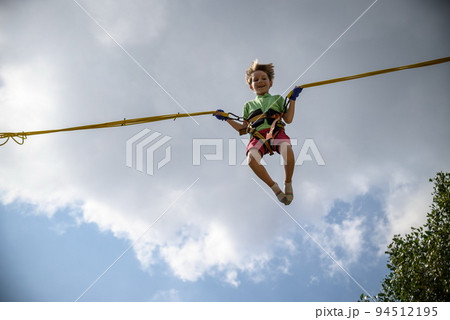 The boy is jumping on a bungee trampoline. A child with insuranc 94512195