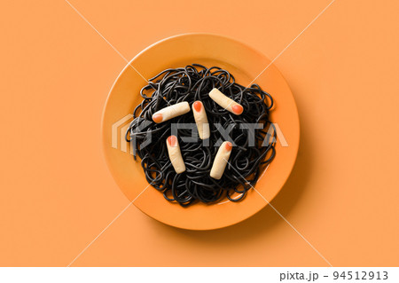 Halloween Italian black pasta decorated funny spiders in orange plate on orange . 94512913