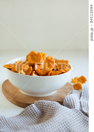 red chanterelle mushrooms in a white plate on a light gray table 94513094
