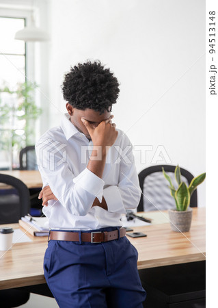 Tired male office worker rubbing forehead Tired male office worker rubbing forehead 94513148