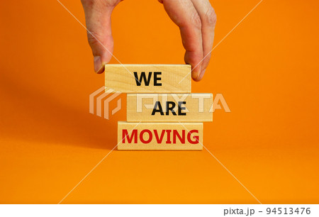 We are moving symbol. Wooden blocks with words 'We are moving'. Beautiful orange background, businessman hand. Business, we are moving concept, copy space. 94513476