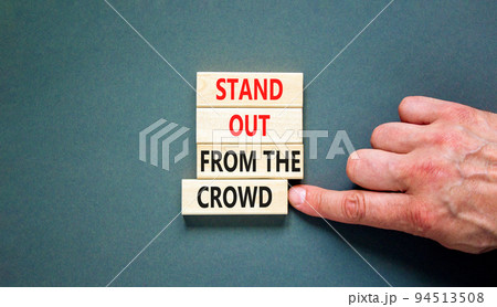 Stand out from the crowd symbol. Concept words Stand out from the crowd on wooden blocks on beautiful grey table grey background. Businessman hand. Business, stand out from the crowd concept 94513508