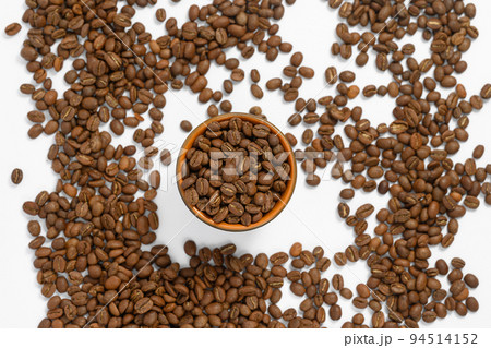 Fragrant roasted coffee beans on a white background and a small cup. Fragrant roasted coffee beans on a white background and a small cup. 94514152