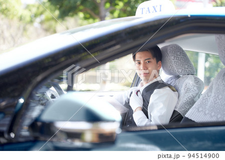 笑顔で視線を向ける若いタクシードライバー 94514900