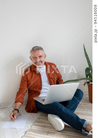 A bearded man in terracotta shirt working on the project and looking involved A bearded man in terracotta shirt working on the project and looking involved 94516009