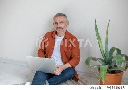 Bearded man in terracotta shirt working from home Bearded man in terracotta shirt working from home 94516013