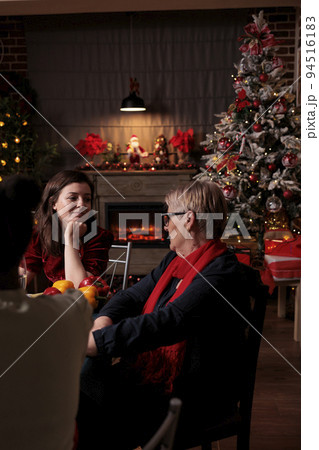 Daughter talking with mom at christmas festive dinner, family having conversation. Xmas celebration in beautiful decorated place with warm evening candle light, fir tree, garlands on background 94516183