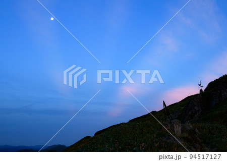 夜明けの空と山肌のシルエットと満月・谷川岳 94517127