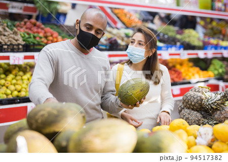 Portrait of latin couple wearing medical masks in supermarket 94517382