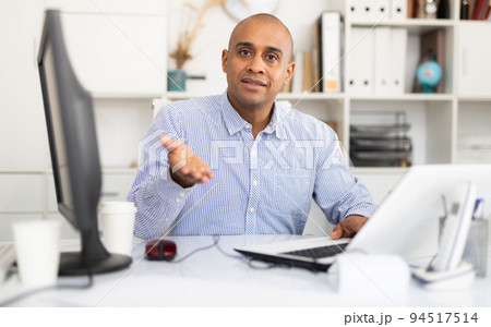 Hispanic confident man working in modern office full of light 94517514
