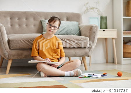 Cute Girl With Down Syndrome Sitting On Floor 94517787