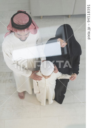 Portrait of a young happy Arabian Muslim family couple with a son in traditional clothes spending time together 94518391