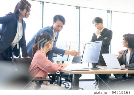モニターを指さしながら打ち合わせをするビジネスパーソン 94519163