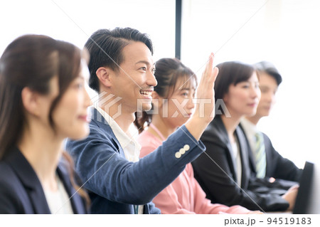 デスクに着席して手を挙げるビジネスパーソン　セミナー　研修　会議　ビジネスイメージ 94519183