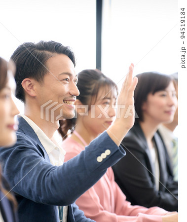 デスクに着席して手を挙げるビジネスパーソン　セミナー　研修　会議　ビジネスイメージ 94519184