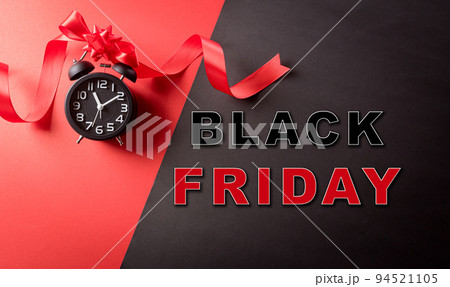 Top view of Black Friday decoration made from alarm clock,  ribbon on red and black background. Shopping concept boxing day and Black Friday composition. 94521105