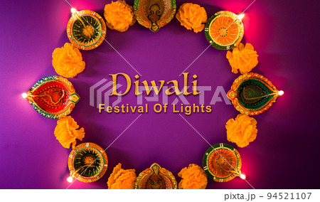 Happy Diwali - Clay Diya lamps lit during Dipavali, Hindu festival of lights celebration. Colorful traditional oil lamp diya on purple background Happy Diwali - Clay Diya lamps lit during Dipavali, Hindu festival of lights celebration. Colorful traditional oil lamp diya on purple background 94521107