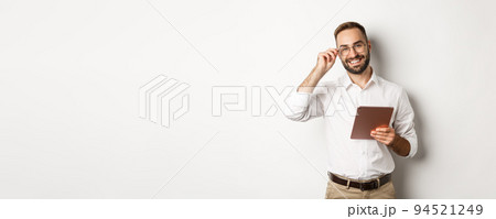 Confident business man working on digital tablet, smiling happy, standing over white background Confident business man working on digital tablet, smiling happy, standing over white background 94521249