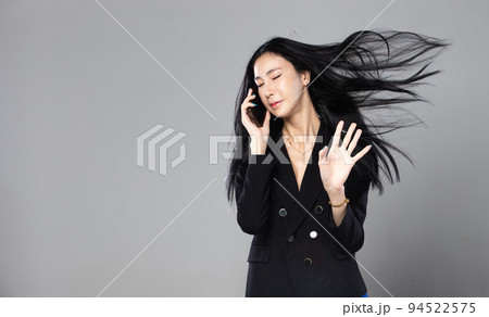 Asian Transgender Woman with long black straight hair, wind blow throw in the Air. Female hold phone against wind storm, feeling fashion sensual sexy, gray background isolated copy space Asian Transgender Woman with long black straight hair, wind blow throw in the Air. Female hold phone against wind storm, feeling fashion sensual sexy, gray background isolated copy space 94522575