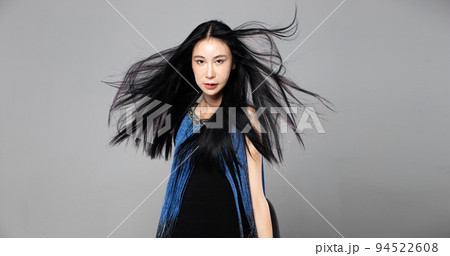 Asian Transgender Woman with long black straight hair, wind blow throw in the Air. Female spin turn around and wear blue fashion sensual sexy dress, gray background isolated copy space Asian Transgender Woman with long black straight hair, wind blow throw in the Air. Female spin turn around and wear blue fashion sensual sexy dress, gray background isolated copy space 94522608
