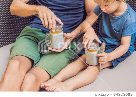 Father and son eat dessert with chia seeds and mangoes by the pool in the morning. healthy eating, vegetarian food, diet and people concept Father and son eat dessert with chia seeds and mangoes by the pool in the morning. healthy eating, vegetarian food, diet and people concept 94525085