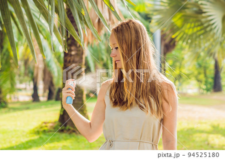 Woman spraying insect repellent on skin outdoor 94525180