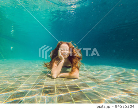 Woman at the bottom of the pool, she dives under the water 94525204