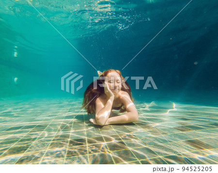 Woman at the bottom of the pool, she dives under the water 94525205