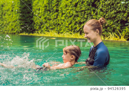 Woman swimming instructor for children is teaching a happy boy to swim in the pool Woman swimming instructor for children is teaching a happy boy to swim in the pool 94526395