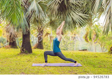 woman practicing yoga in a tropical park 94526783