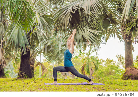 woman practicing yoga in a tropical park 94526784